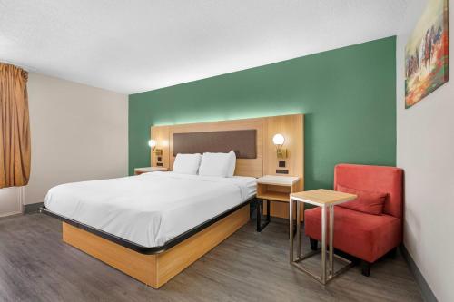 Baymont by Wyndham Richmond KY في ريتشموند: غرفة فندق بها سرير وكرسي أحمر