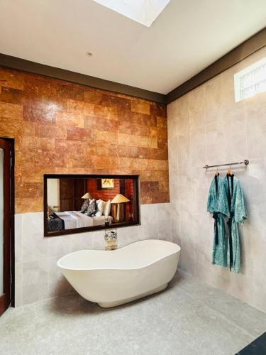 a bathroom with a tub and a bed in a mirror at Uma Galih Ubud Villa in Ubud