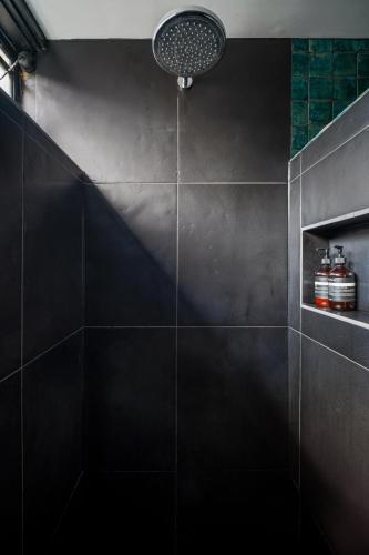 a bathroom with a shower with black tiles at Garden oasis in the heart of Fitzroy in Melbourne