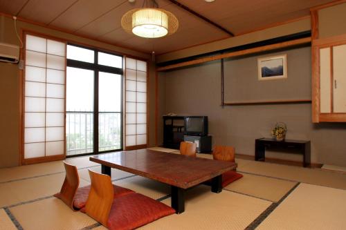 Una sala de estar con una mesa y sillas de madera. en Ryokan Kintoki, en Aso