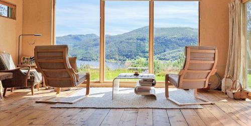 two chairs and a table in front of a large window at Self-Built Cabin With Views Over Leirvik in Leirvik