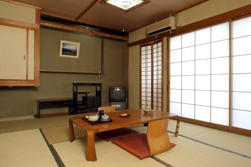 Una sala de estar con una mesa y un televisor. en Ryokan Kintoki, en Aso