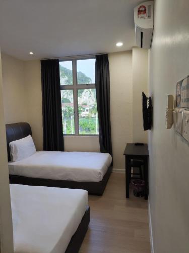 een hotelkamer met twee bedden en een raam bij T&S Management House in Gua Musang