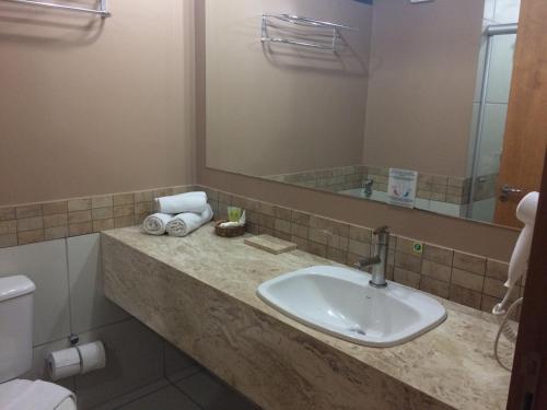 y baño con lavabo y espejo. en Apartamento Suites Le Jardin Caldas Novas Goiás, en Caldas Novas