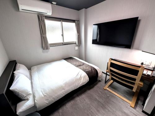 a bedroom with a bed and a flat screen tv at アミスタホテルアネックス in Matsuura