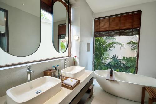 a bathroom with a tub and a sink and a mirror at Amayi Resort Nusa Dua in Nusa Dua