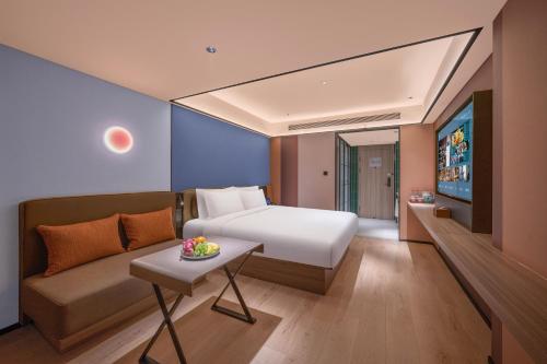 a hotel room with a bed and a couch at Orange Hotel Beijing Xi'erqi in Beijing