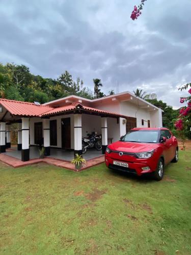 a red car parked in front of a house at Diyaluma Villa Resort in Koslanda