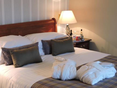 a bed with a white comforter and pillows at Alexandra Hotel in Fort William