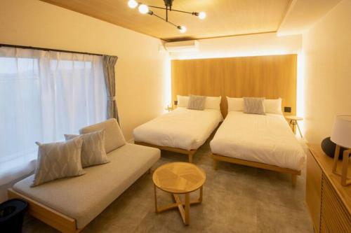 a room with two beds and a couch and a window at Yadoya YADOKARI in Pippu