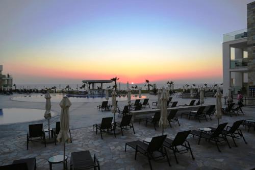 a group of tables and chairs on the beach at sunset at Amphora Hotel & Suites in Paphos