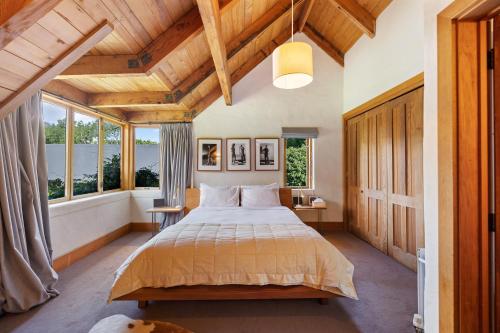 a bedroom with a large bed and two windows at Wharenui Holiday Home by MajorDomo in Arrowtown
