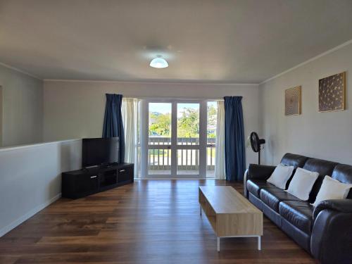 een woonkamer met een zwarte bank en een tv bij Pure Motel in Rotorua