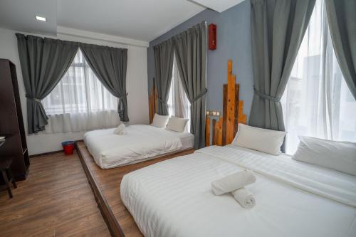 two beds in a room with two windows at De Grand Boutique Hotel in Sepang