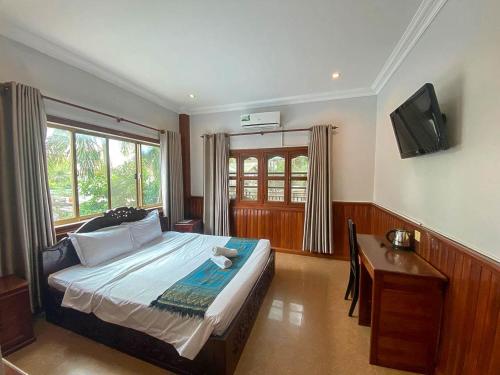 ein Schlafzimmer mit Bett, Schreibtisch und Fernseher in der Unterkunft Mony Soksan Residence in Siem Reap