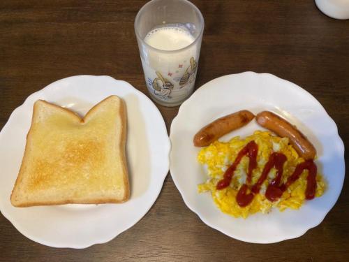 a table with two plates of breakfast food with sausage and eggs at 安房リゾート旅館 臨海臥龍 in Kamogawa