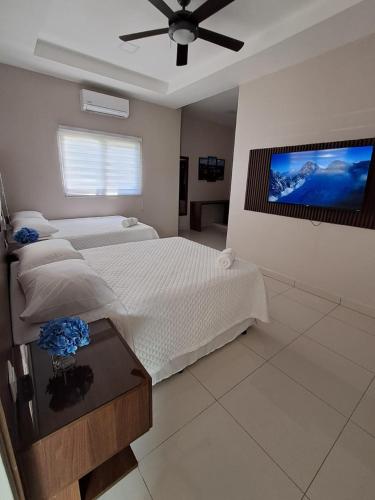 a bedroom with two beds and a flat screen tv at Hostal Boutique Isabel in Managua