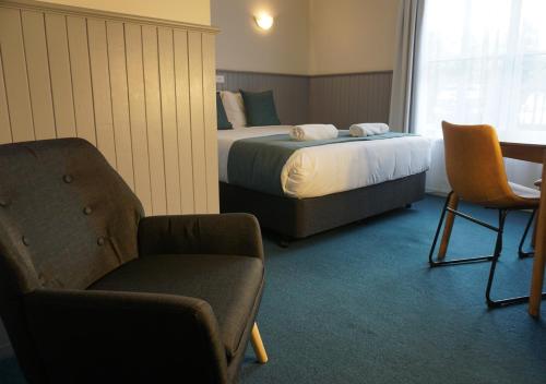 a hotel room with two beds and a chair at Central Motel Port Fairy in Port Fairy