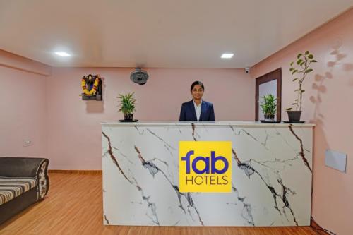 プネにあるVia The Heavenのアイーダホテルの看板を持ってカウンターの後ろに立っている女性