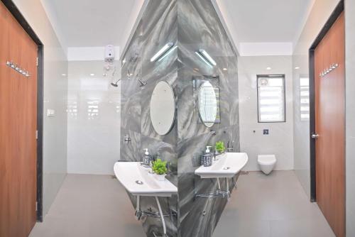 Villa With Turf & Indoor Games في Malavli: حمام به مغسلتين ومرآتين