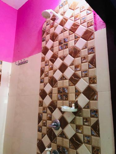 a bathroom with a tiled shower with a pink wall at Umananda Hotel and Lodge in Birtamode