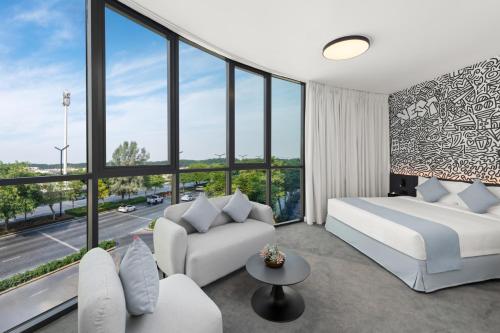 a bedroom with a bed and a couch and windows at Nest Hotel, Aljada in Sharjah