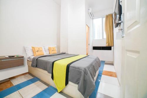 een slaapkamer met een bed met een gele en grijze deken bij The Panorama Suites by MHM in Jakarta