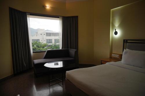 a hotel room with a bed and a chair and a window at Darling Residency in Vellore