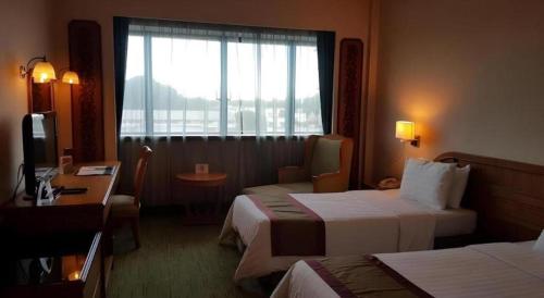 Una habitación de hotel con dos camas y una ventana. en The CentrePoint Hotel, en Kampong Kiulap