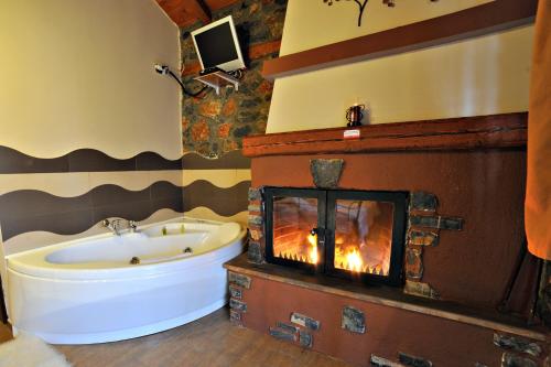 a bathroom with a tub and a fireplace at Guesthouse Nifada tou Vorra in Palaios Agios Athanasios