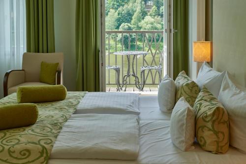 a bedroom with a large bed and a balcony at Hotel Elbresidenz an der Therme in Bad Schandau