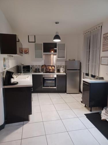 een keuken met een zwart-wit aanrecht en apparatuur bij Le Refuge in Saint-Aignan