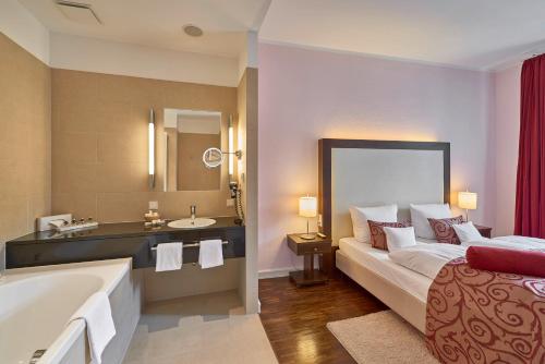 a bathroom with a tub and a bed and a sink at Hotel Elbresidenz an der Therme in Bad Schandau