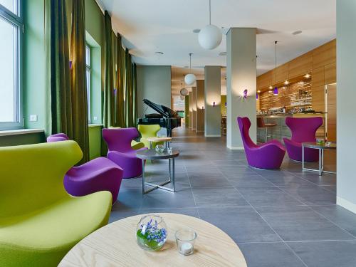 a lobby with purple and green chairs and tables at Hotel Elbresidenz an der Therme in Bad Schandau