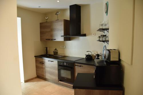 a kitchen with wooden cabinets and a black counter top at Sous le Clocher in Marseille
