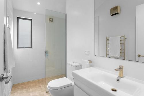 a white bathroom with a toilet and a sink at White Sands Haven - Omaha Family Escape in Omaha