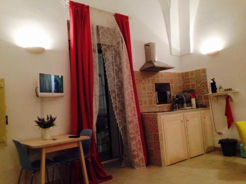 a room with red curtains and a table and a kitchen at L'alcova di Garibaldi in Ostuni