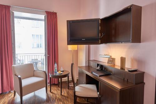 a hotel room with a desk and a tv at Hotel Elbresidenz an der Therme in Bad Schandau
