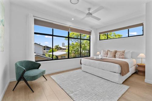 a bedroom with a bed and a chair and windows at Palm Beach Retreat: Plunge Pool & Coastal Luxe in Gold Coast