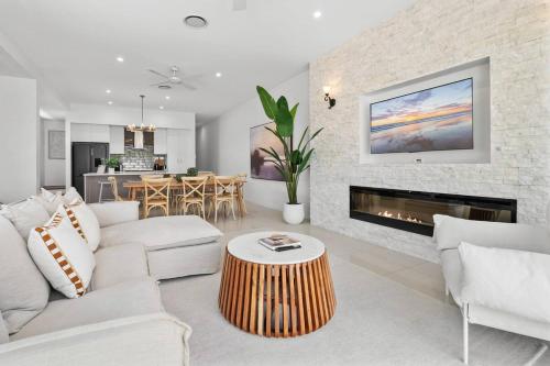 a living room with white furniture and a fireplace at Palm Beach Retreat: Plunge Pool & Coastal Luxe in Gold Coast
