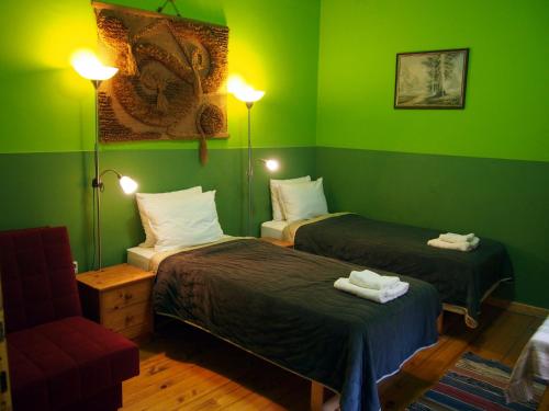 Habitación verde con 2 camas y silla en Guest Accommodation Etno Konak Tašana, en Niš