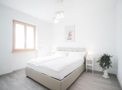 een witte slaapkamer met een wit bed en een raam bij Appartamenti Ora e Peler in Riva del Garda