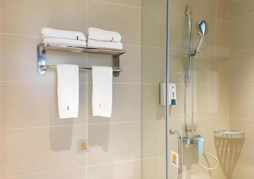 a bathroom with a shower with towels on a wall at JTOUR Inn Huangshi North Station Cihu Scenic Area in Huangshigang