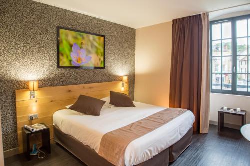 a hotel room with a bed and a window at Charme et Caractère Le Turenne in Beaulieu-sur-Dordogne