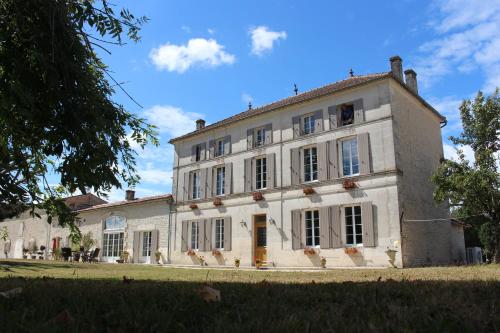 a large white building with windows on a field at Logis de L'Arceau in Celles