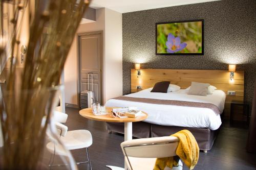 a hotel room with a bed and a table at Charme et Caractère Le Turenne in Beaulieu-sur-Dordogne