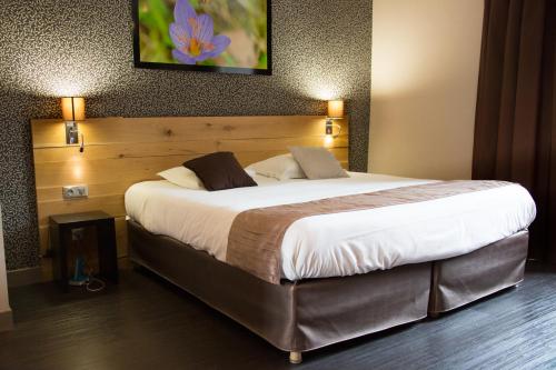 a large bed in a hotel room with two lamps at Charme et Caractère Le Turenne in Beaulieu-sur-Dordogne