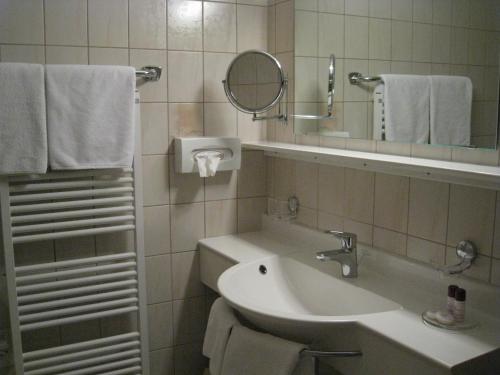 a bathroom with a sink and a mirror and towels at Apart Hotel Garni Strasser in Zell am Ziller