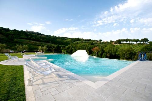 a swimming pool with two chairs in the grass at Moresco Agriturismo in Moresco