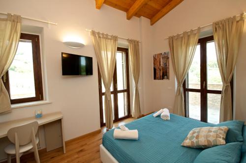 a bedroom with a blue bed and a desk and windows at Moresco Agriturismo in Moresco